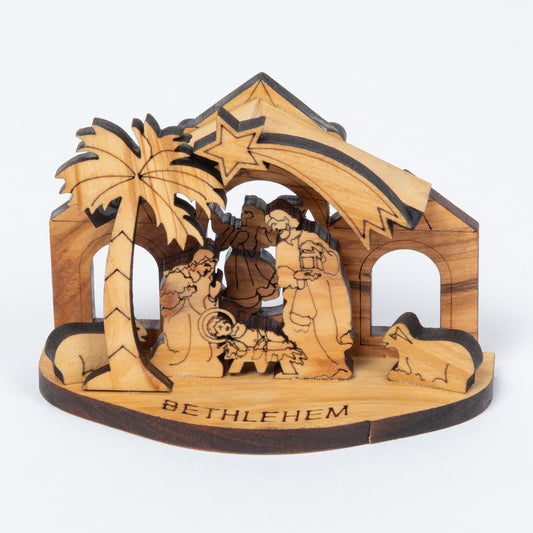 A handcrafted wooden nativity scene stand engraved with 'BETHLEHEM' on the base, featuring a palm tree, star, and figures inside a stable-like structure, photographed on a clean white background.