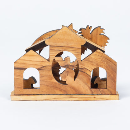 A handcrafted wooden nativity stable miniature with a warm honey-wood grain finish, featuring cutout figures of Mary, Joseph, baby Jesus, and animals, set against a plain white background.