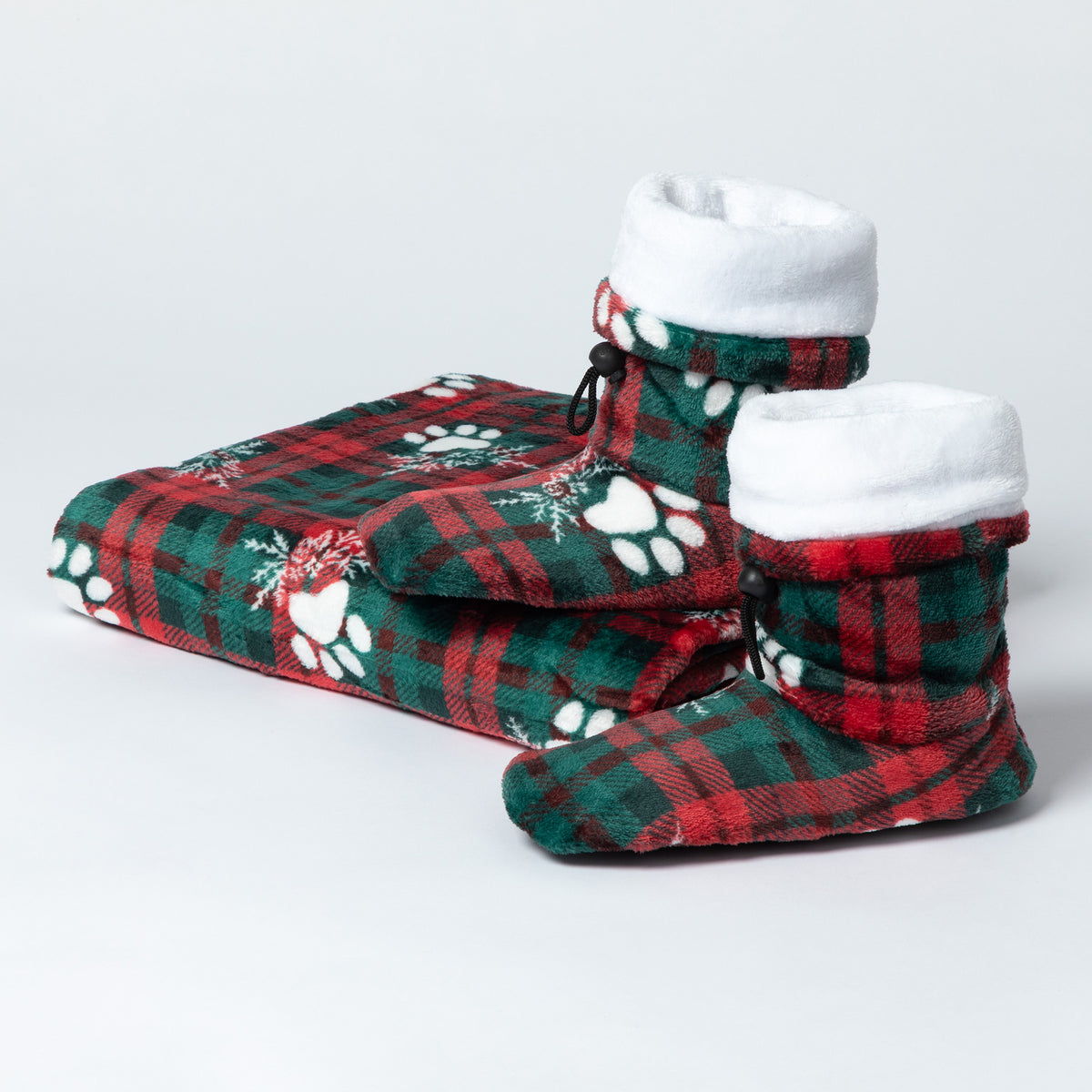 A pair of plush bootie slippers with a red and green plaid pattern, white paw prints, and a white fleece lining, shown on a light gray background.