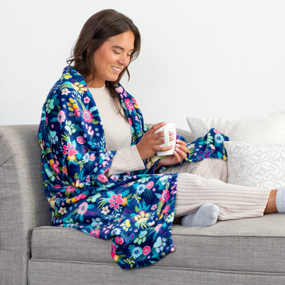 Woman sitting on a couch with a colorful floral blanket and holding a mug.