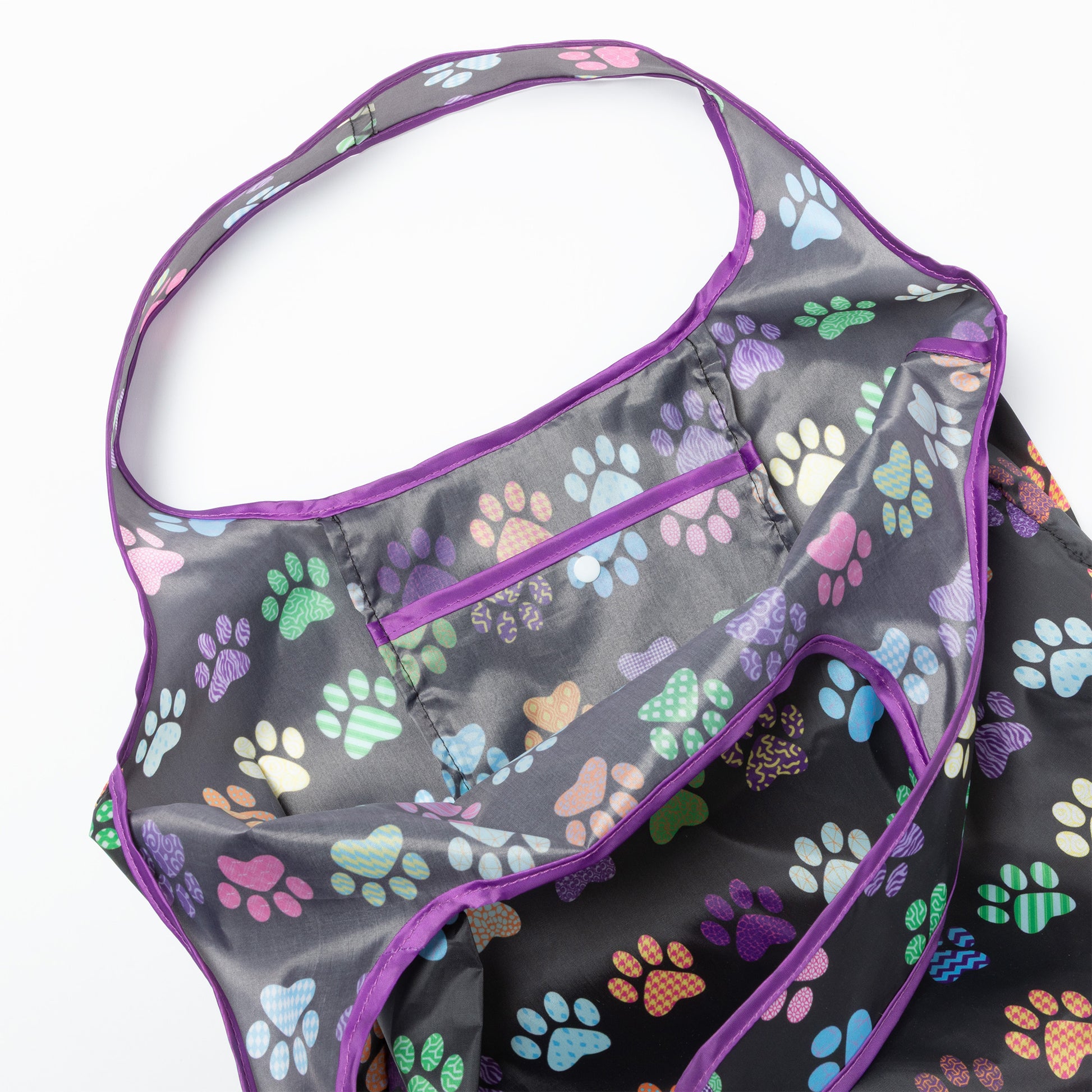 Close up of a reusable shopping bag with purple trim and paw prints all over.