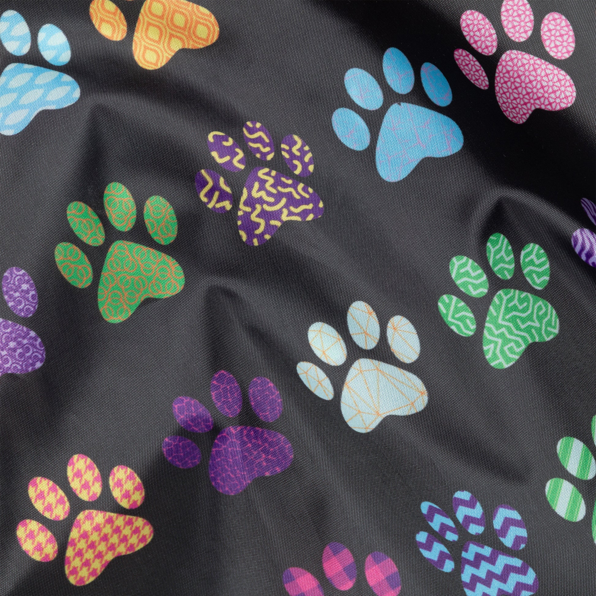 Close up of a black reusable shopping bag with a colorful paw print design.