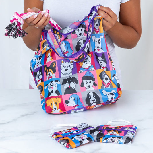 Person holding a colorful dog-patterned tote bag with matching folded totes on a table