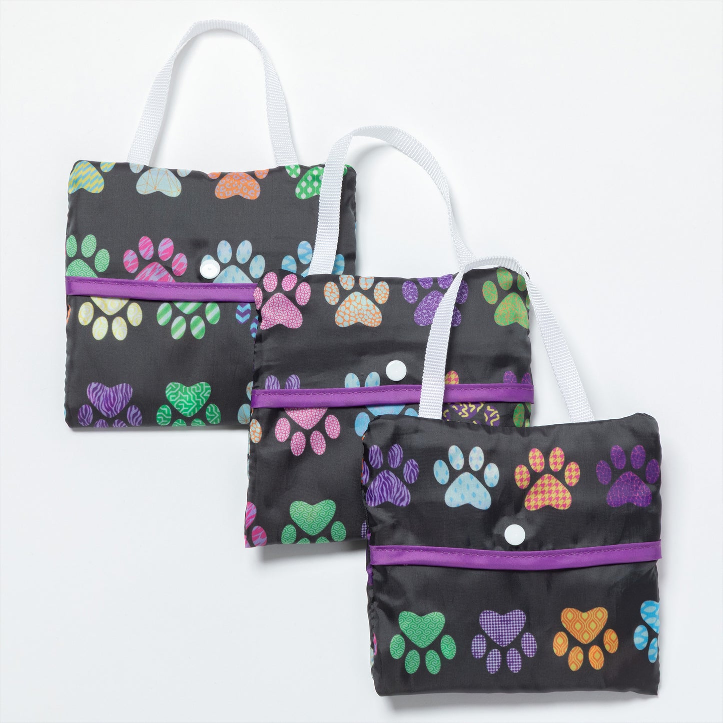 Three folded compact reusable bags with colorful paw prints all over, against a white background.