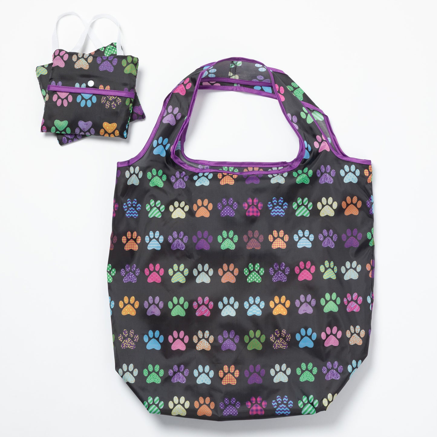 A black reusable bag with colorful paw prints all over, and two folded bags compact next to it, on a white background.