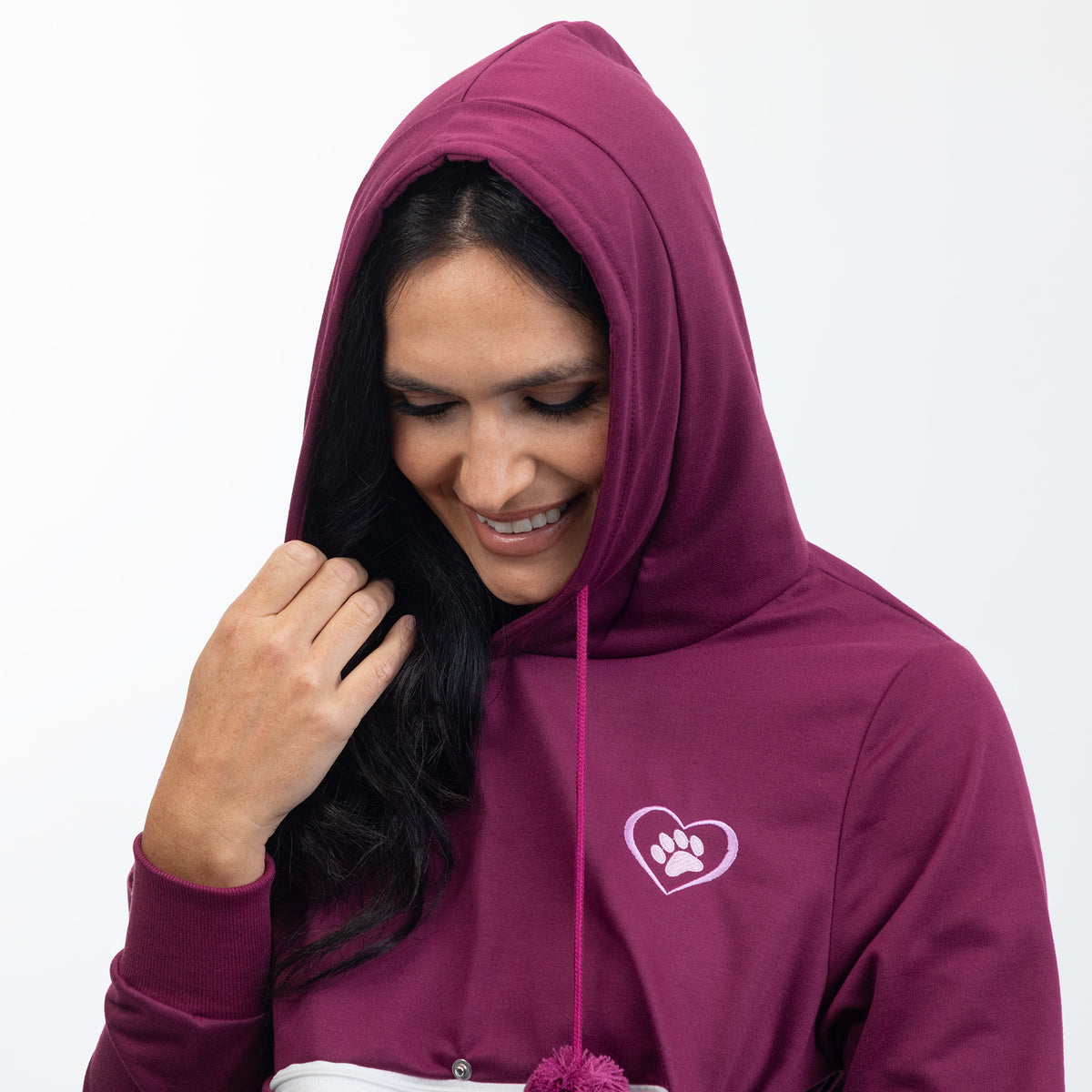 A woman wearing a maroon hooded sweatshirt with a small white paw print inside a heart graphic on the left chest, shown against a plain white background.