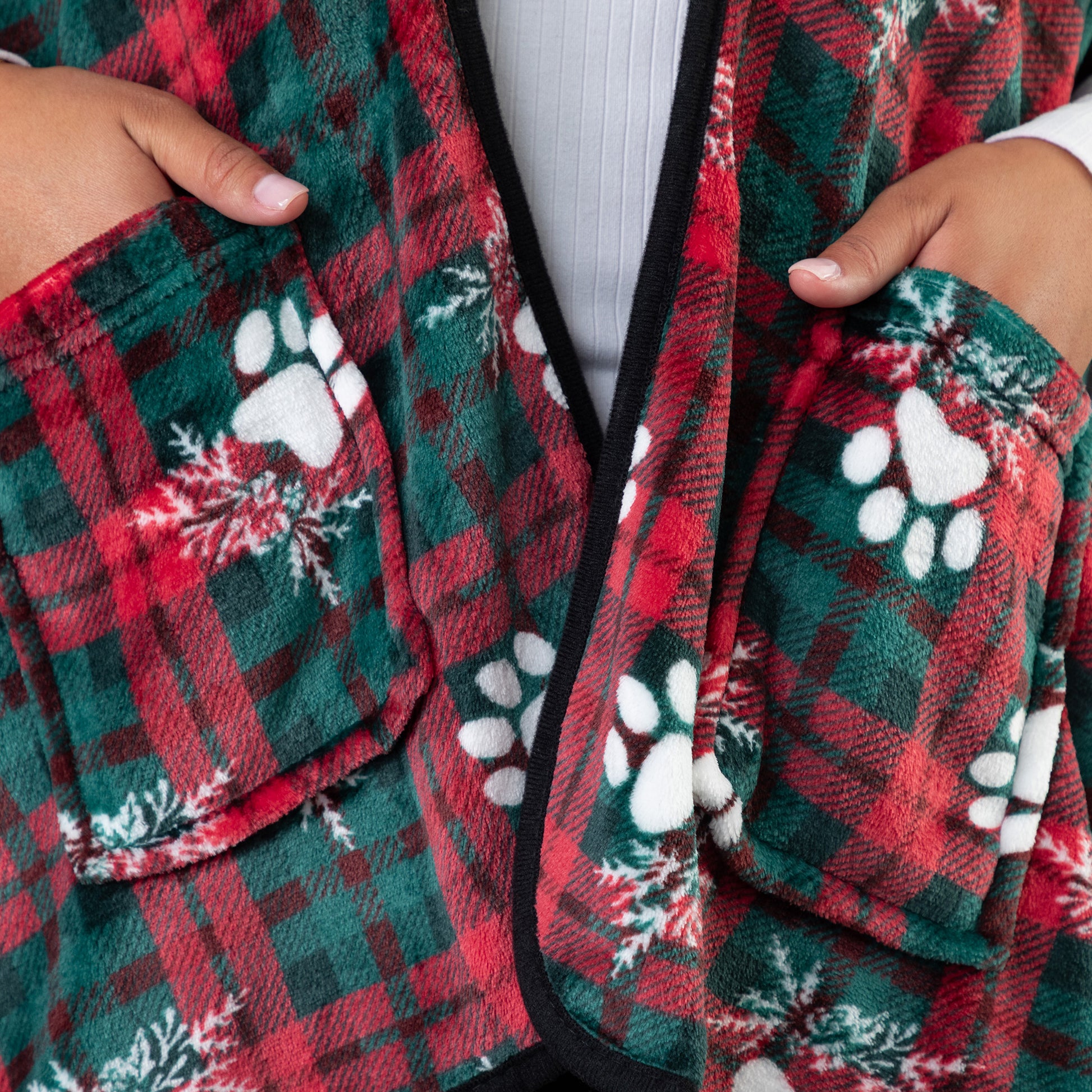 Hands in the two pockets of the wearable blanket shawl. The warm, soft fleece is visible along with the elegant black piping. 