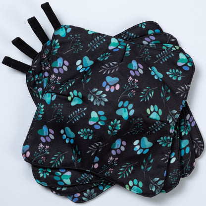 A set of four bowl cozies with various patterns, including a paw print design, paw meadow black
