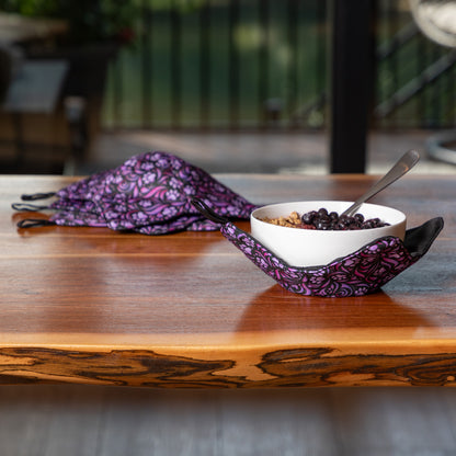 Purple paw symphony bowl cozy on a wooden table with a bowl of food and spoon