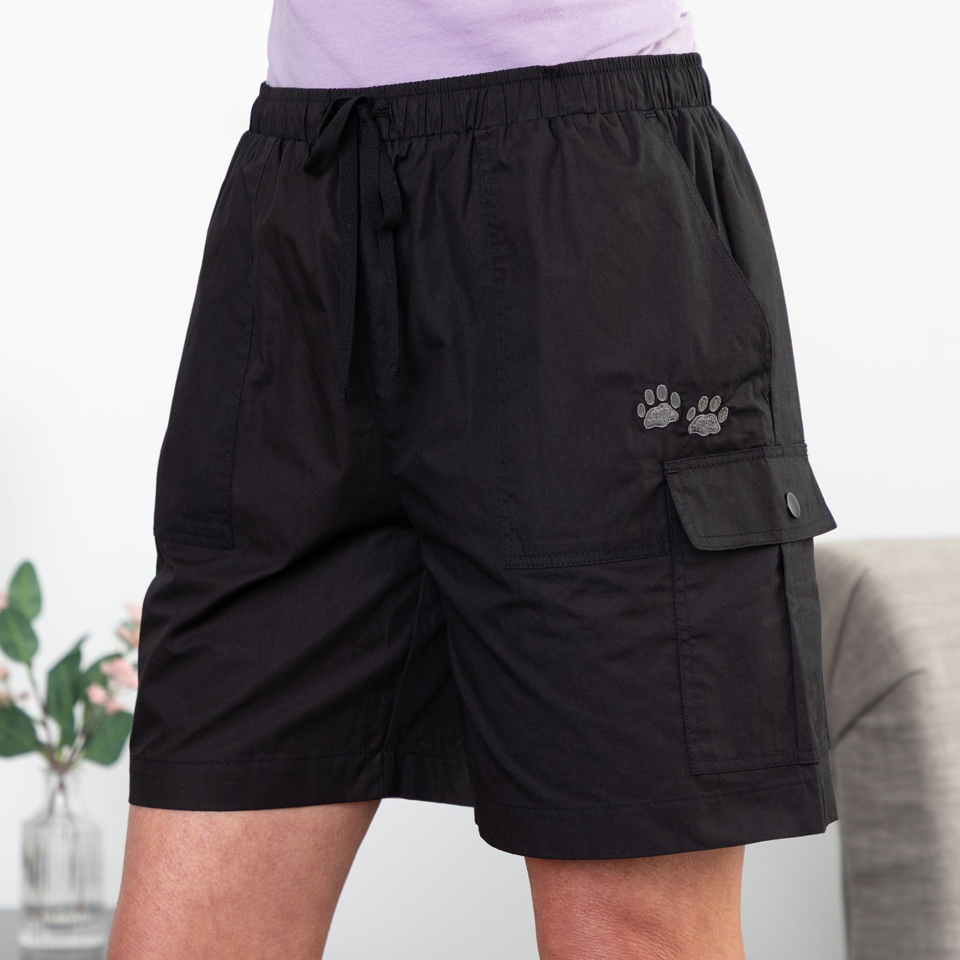 Black cargo shorts with a paw print design on a neutral background