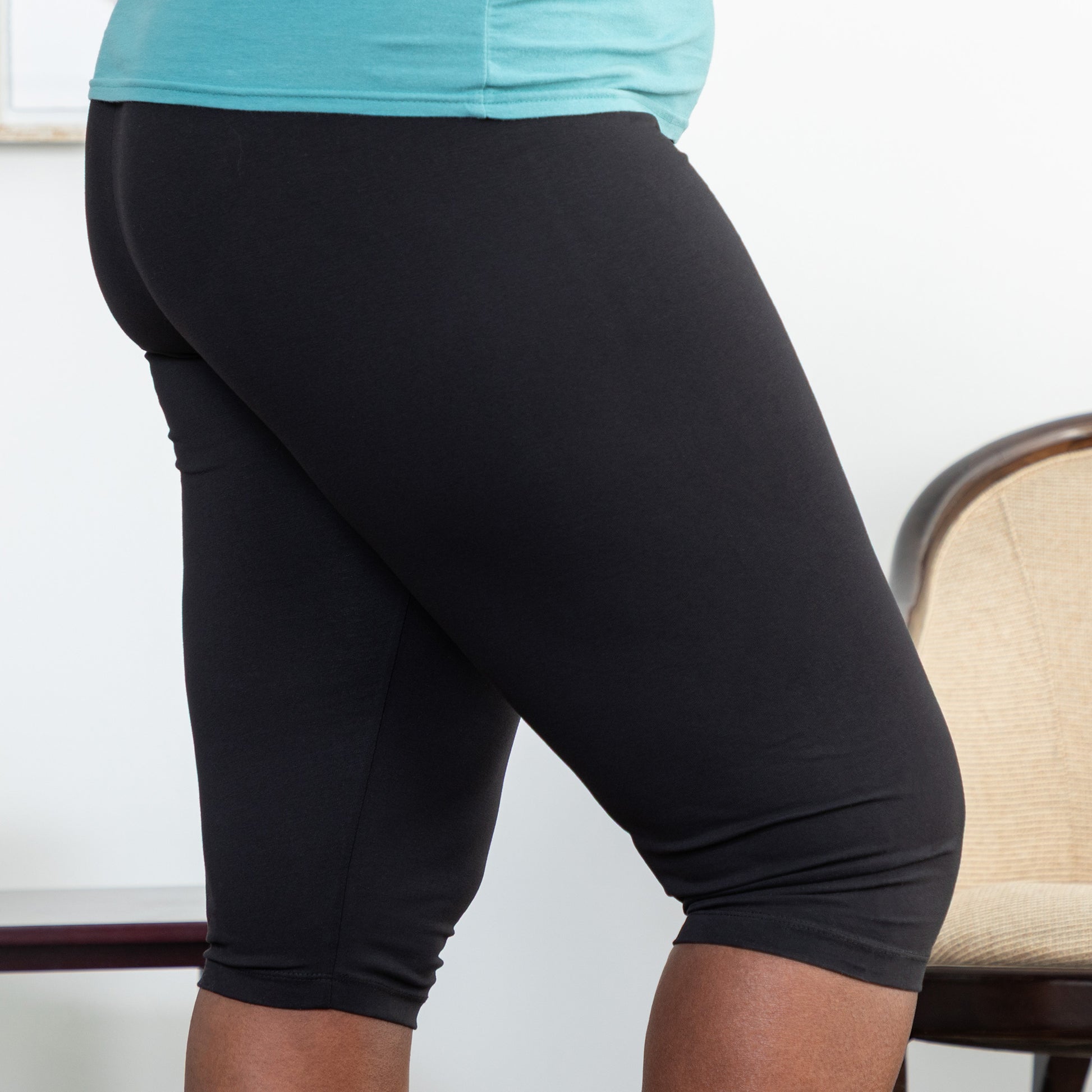 Person wearing black capri leggings with a light blue top, standing indoors.
