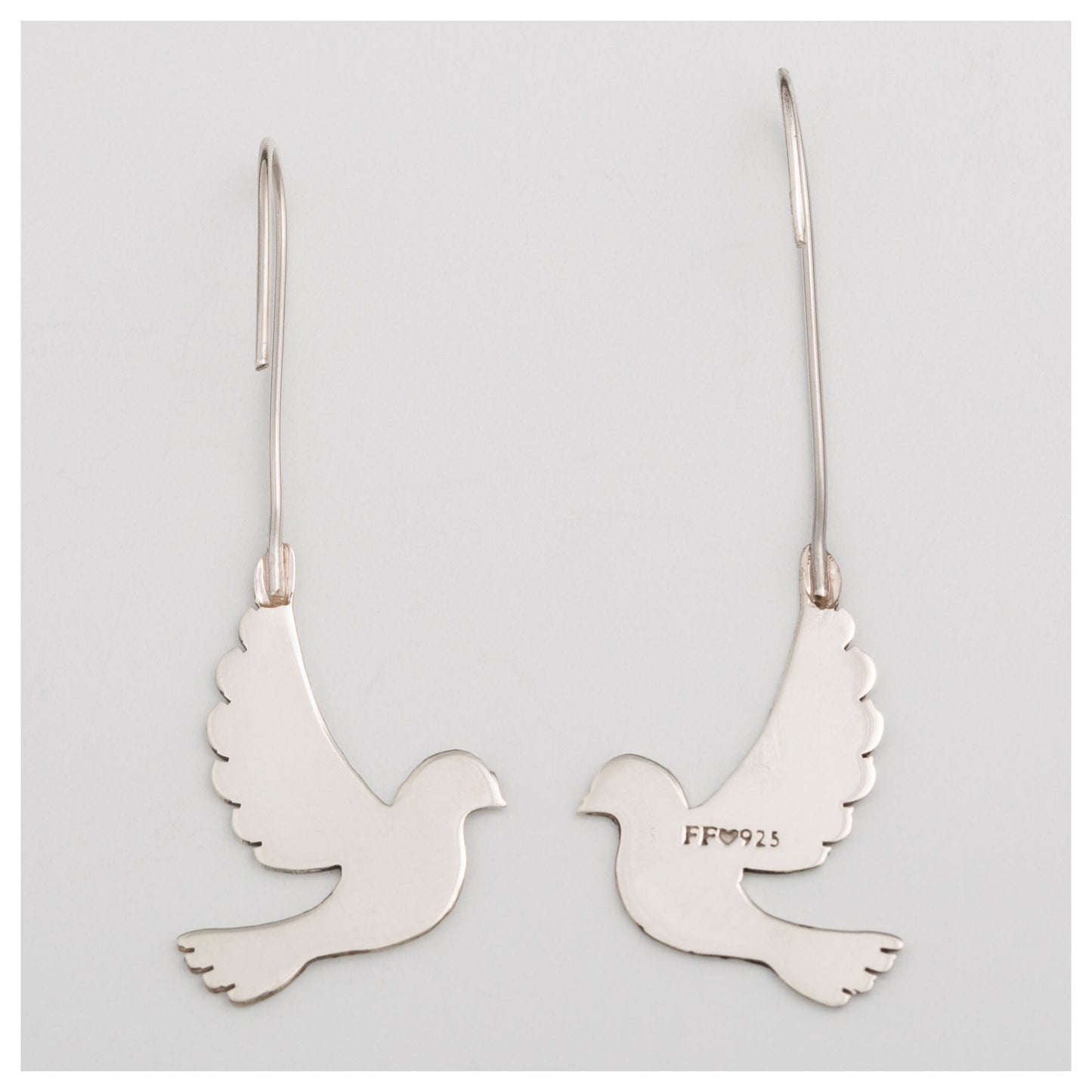 Back of silver dove-shaped earrings on a light gray background