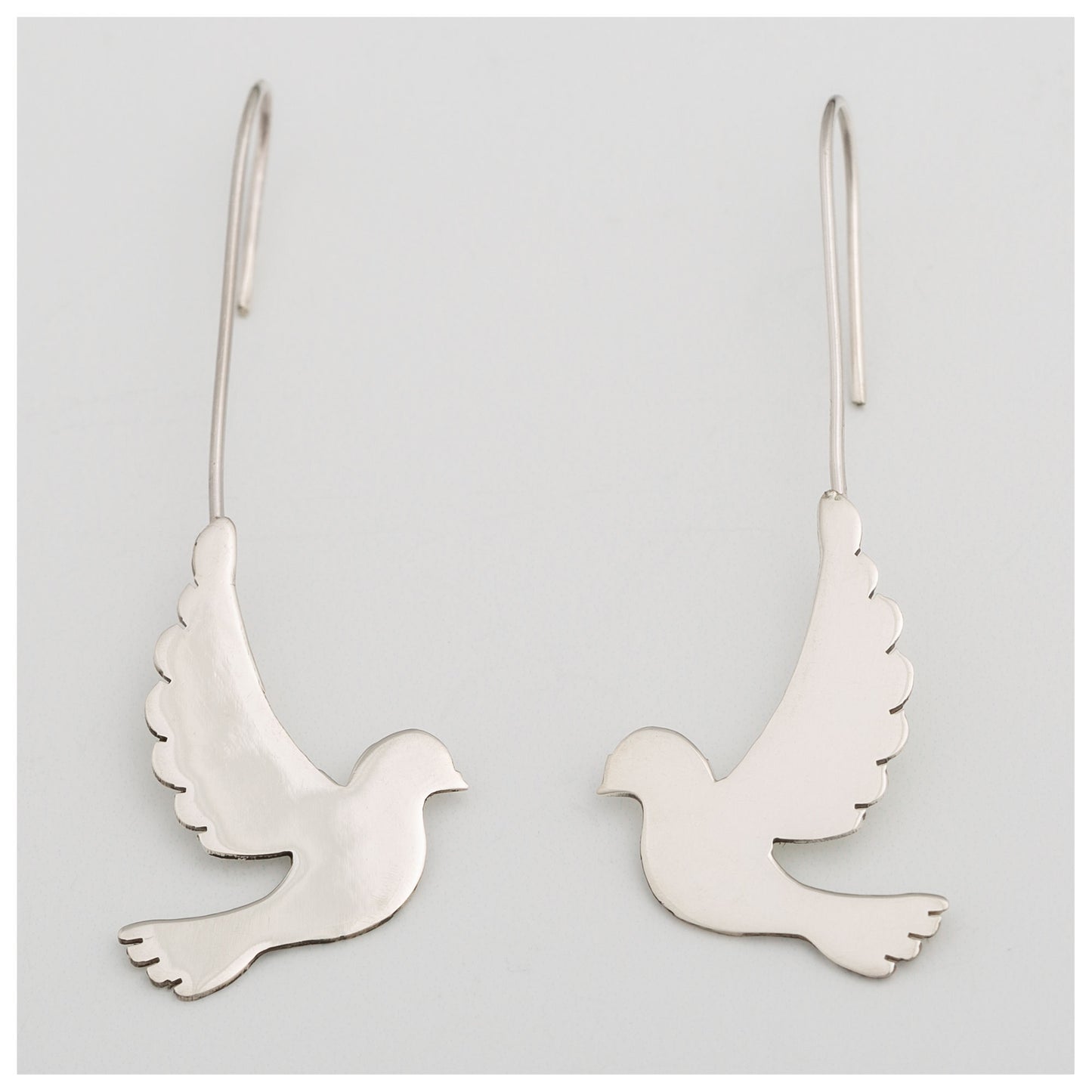Silver dove-shaped earrings on a light gray background