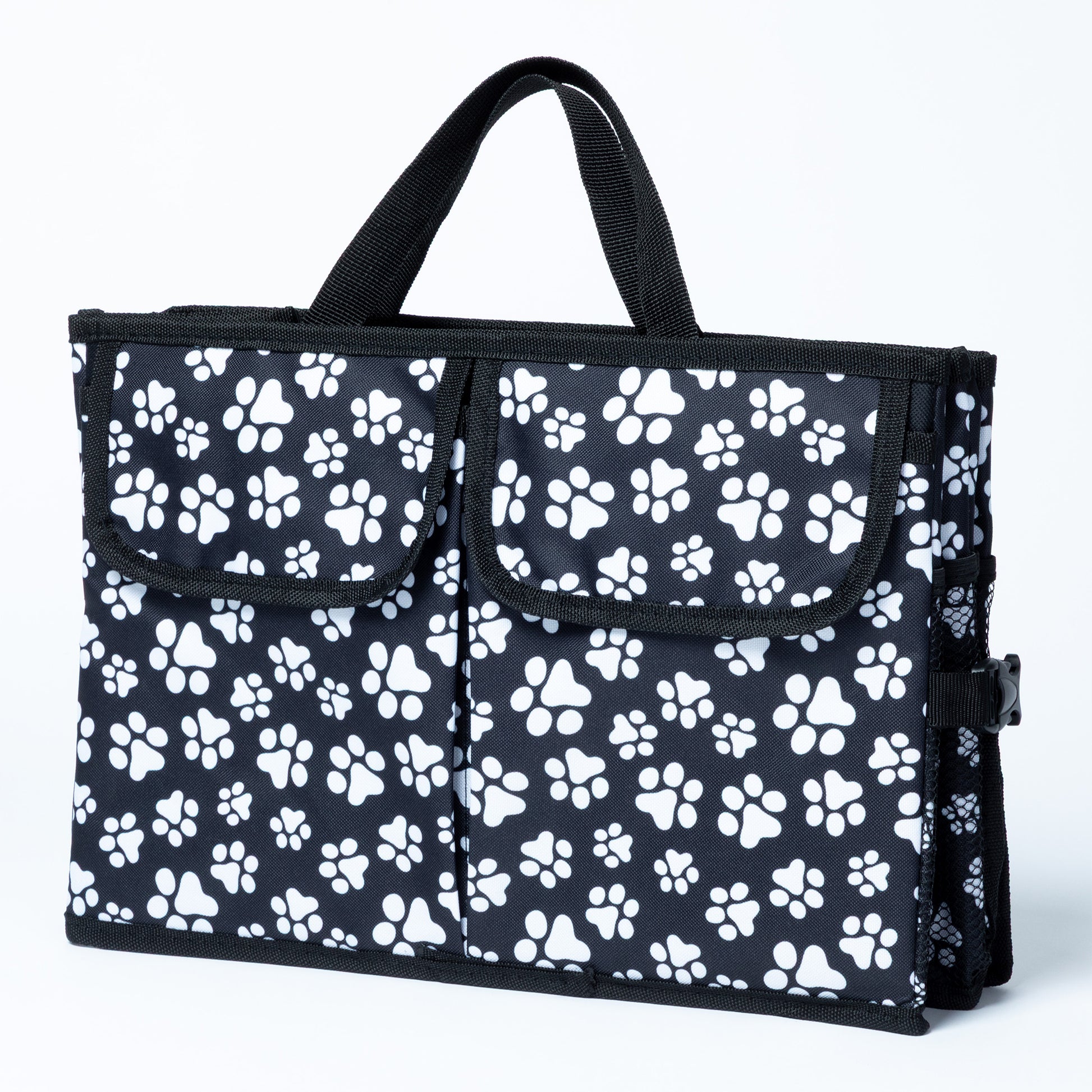White paw print patterned car trunk organizer with pockets on the front, and a mesh pocket on the side, on a white background.