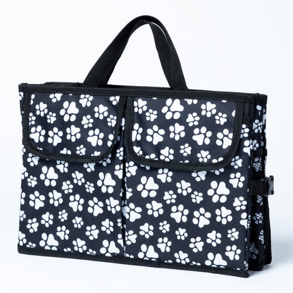 White paw print patterned car trunk organizer with pockets on the front, and a mesh pocket on the side, on a white background.