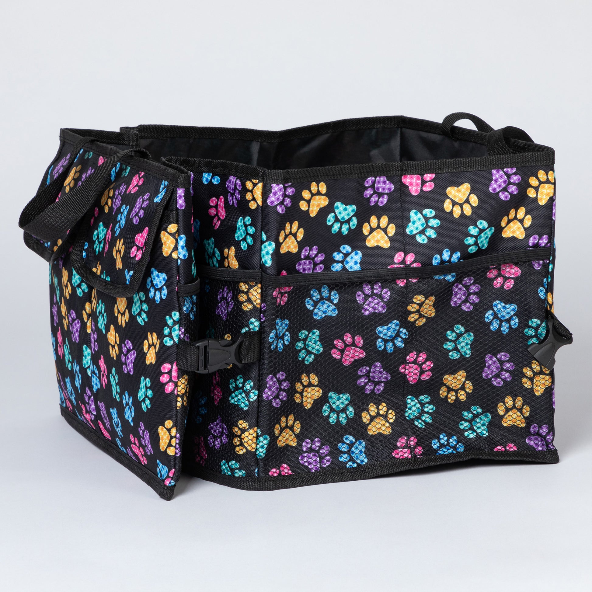 Side view of a colorful paw print patterned  car trunk organizer, with a collapsible side with a buckle, and a side mesh pocket.