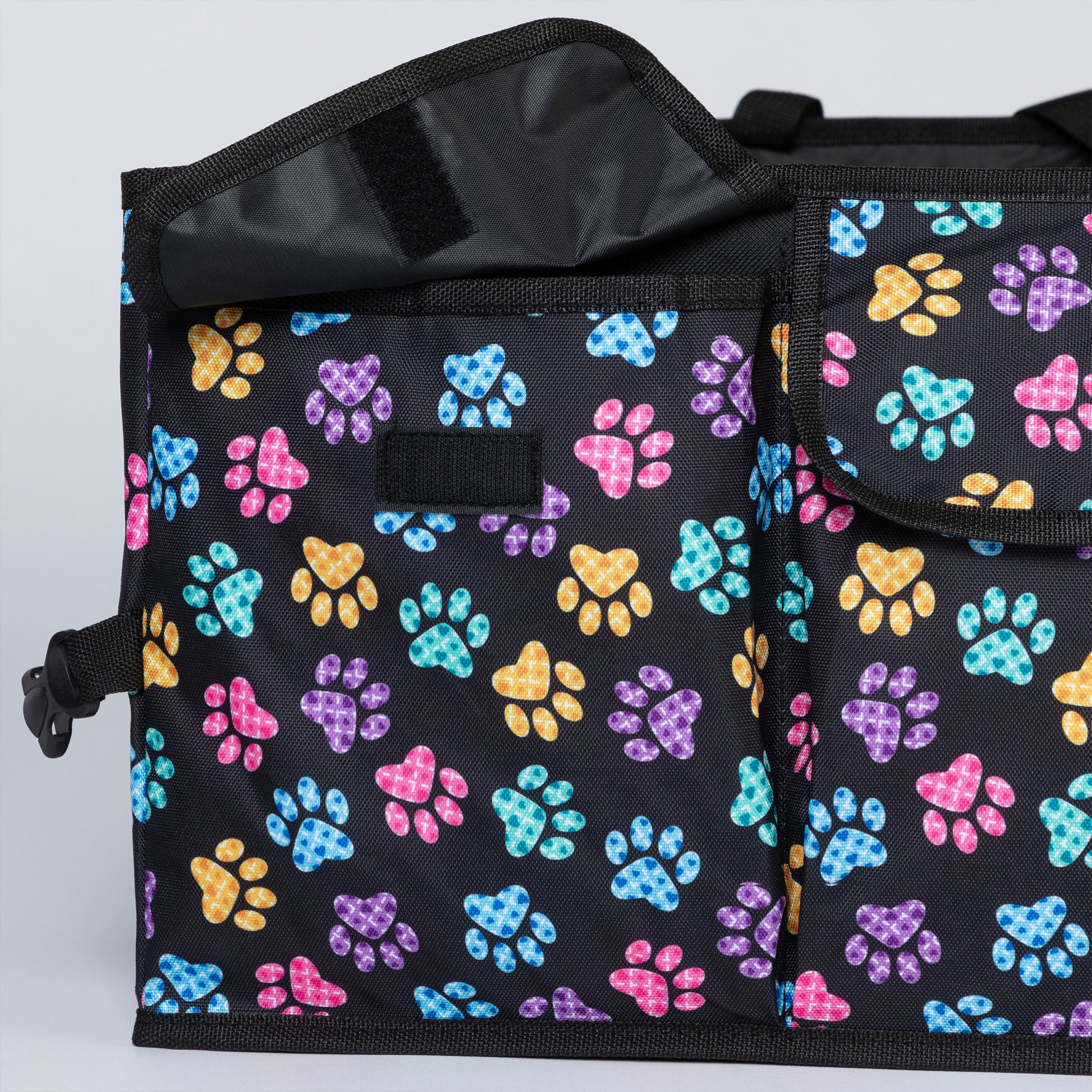 Close up of front pocket with flap closure of a colorful paw printed car trunk organizer.