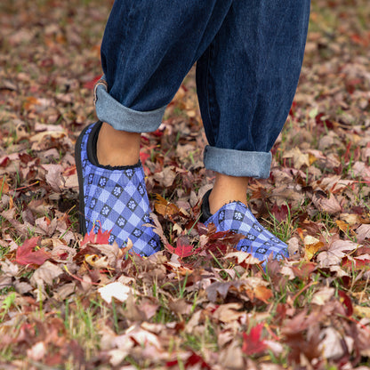 Person wearing periwinkle checkered Slip on shoes on a leaf-covered ground