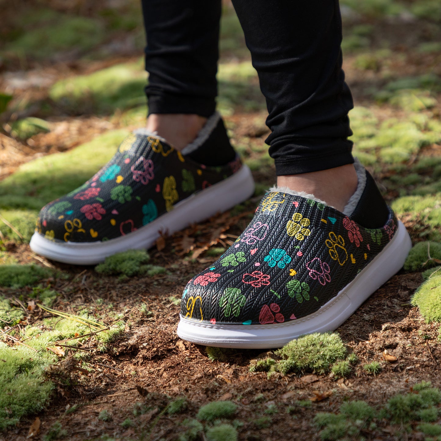 Colorful floral-patterned slipper shoes on a person standing on a natural ground.