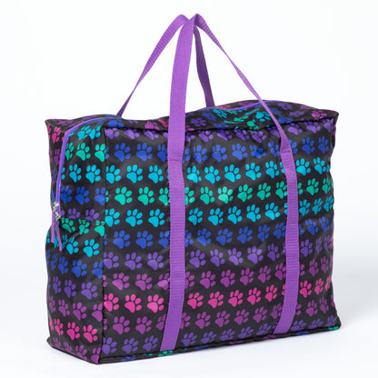 A duffel bag with colorful paw print pattern, purple straps on a white background