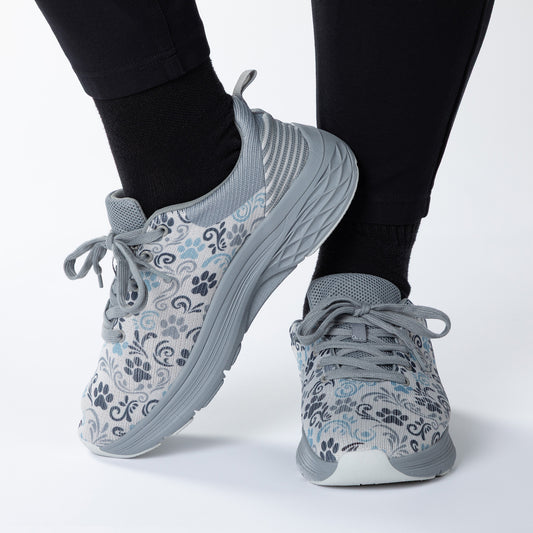 Gray paw print patterned sneakers worn with black leggings on a white background