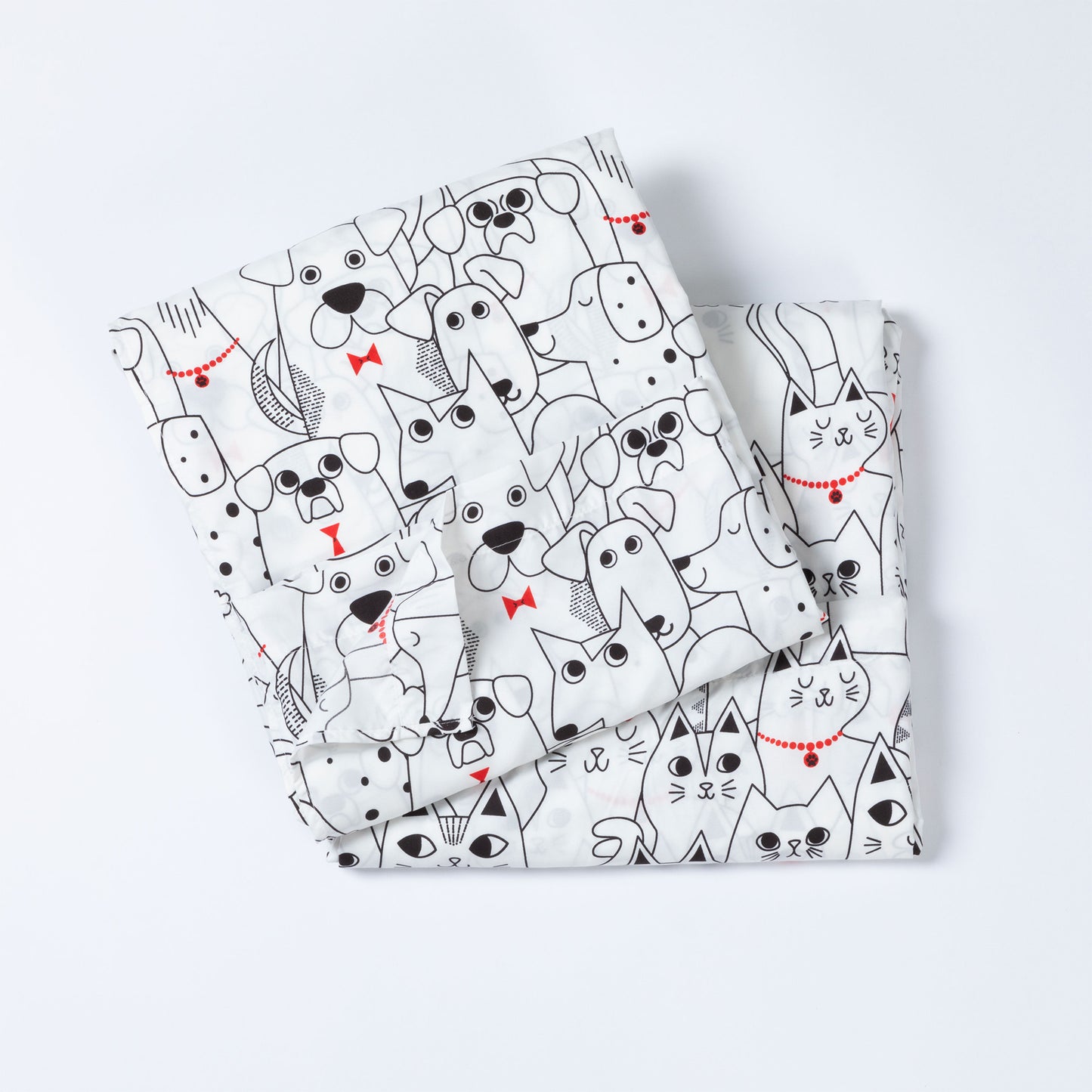 A folded white set of sheets featuring a playful black line-art pattern of various dogs and cats with small red bow ties and collar accents, set against a clean white background.