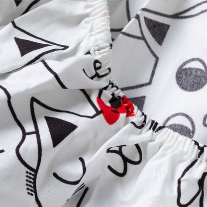 Close-up of a white sheets with a black cat-face line pattern and a small red bow detail near the elasticized waist.