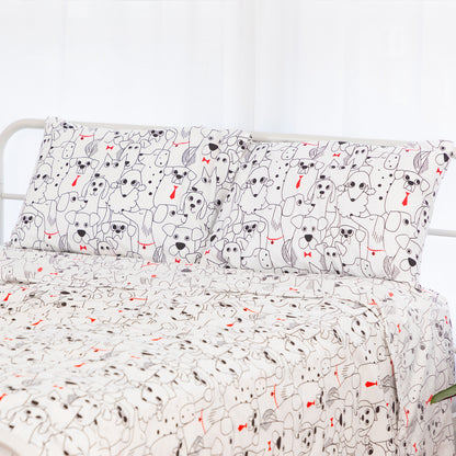 A bed dressed in a white bedding set with a repeating cartoon dog print in black and small red accents, shown against a bright white background.