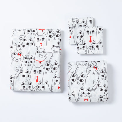 A coordinated bedding or fabric set arranged on a light gray background, featuring a large folded piece and three smaller folded pieces. The fabric has a white base with an all-over black line-art cat pattern, with a few cats wearing small red neckties or bowties.