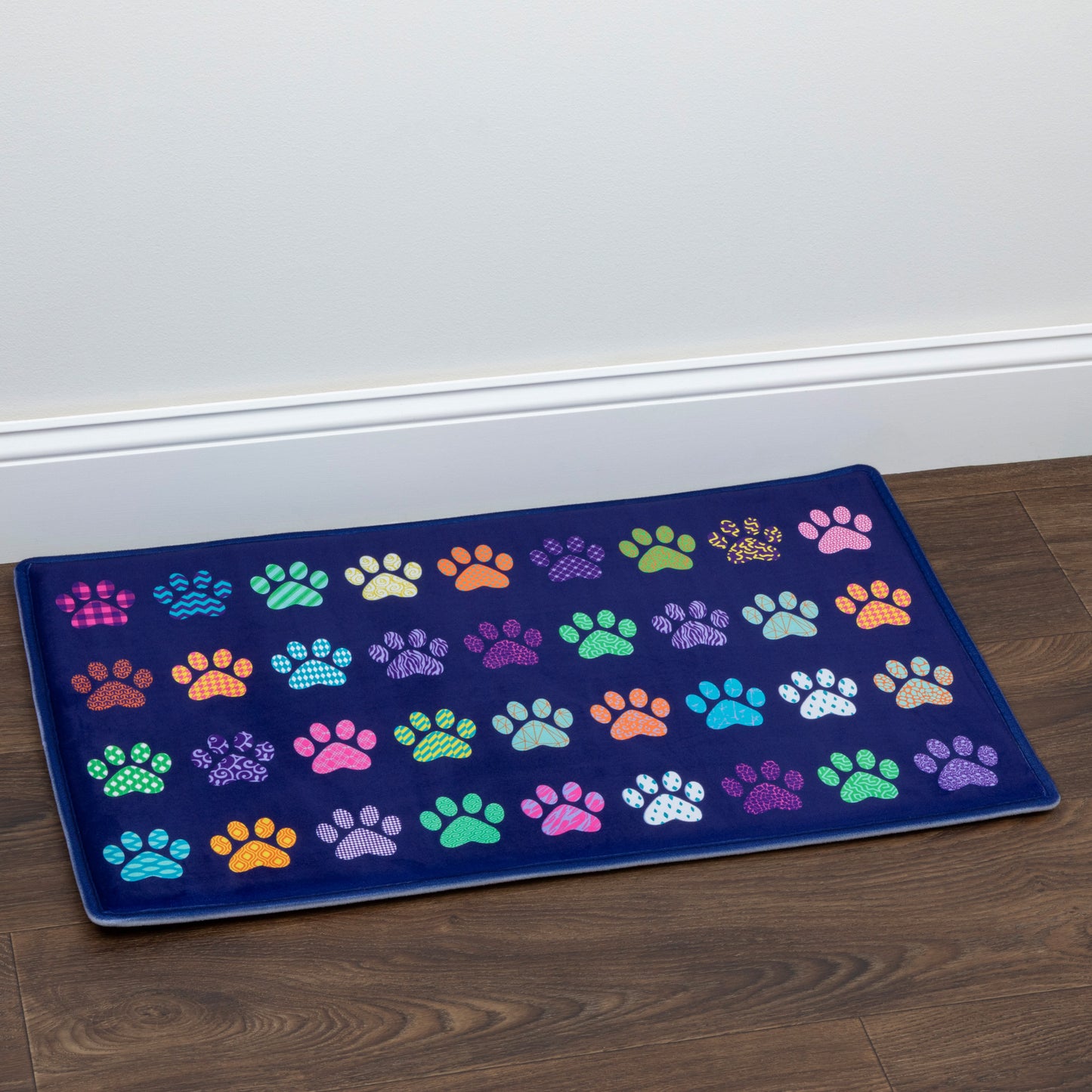 Colorful paw print mat on a wooden floor with a white wall background