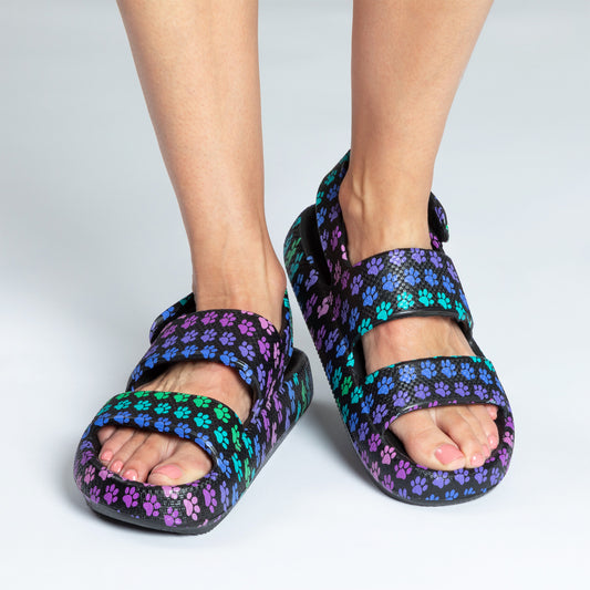 Colorful sandals with a paw print design on a person's feet.