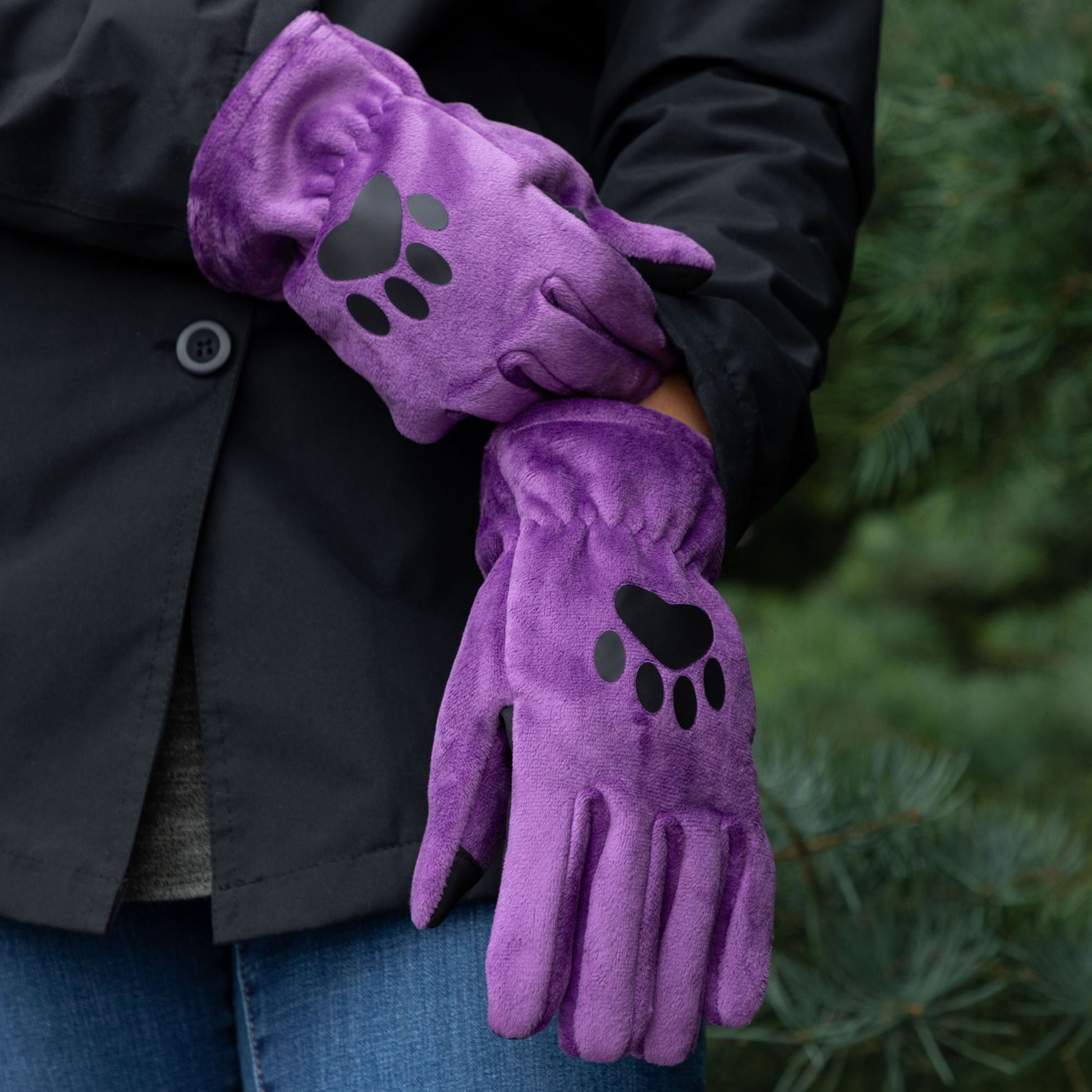 Purple gloves with paw prints held by a person against a blurred green background