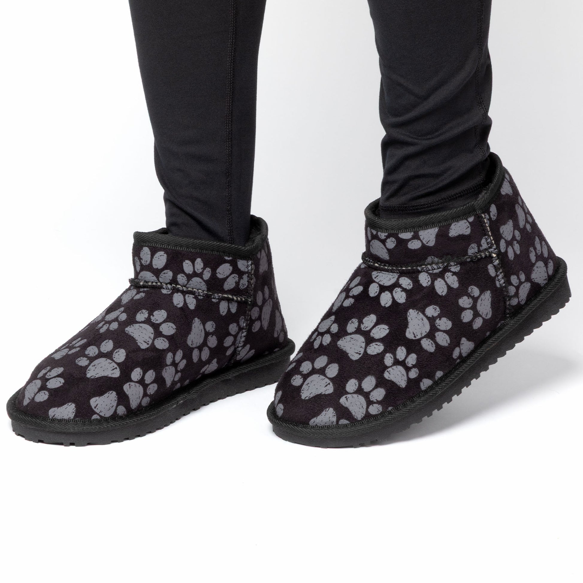 Black boots with gray paw prints worn with black pants on a white background