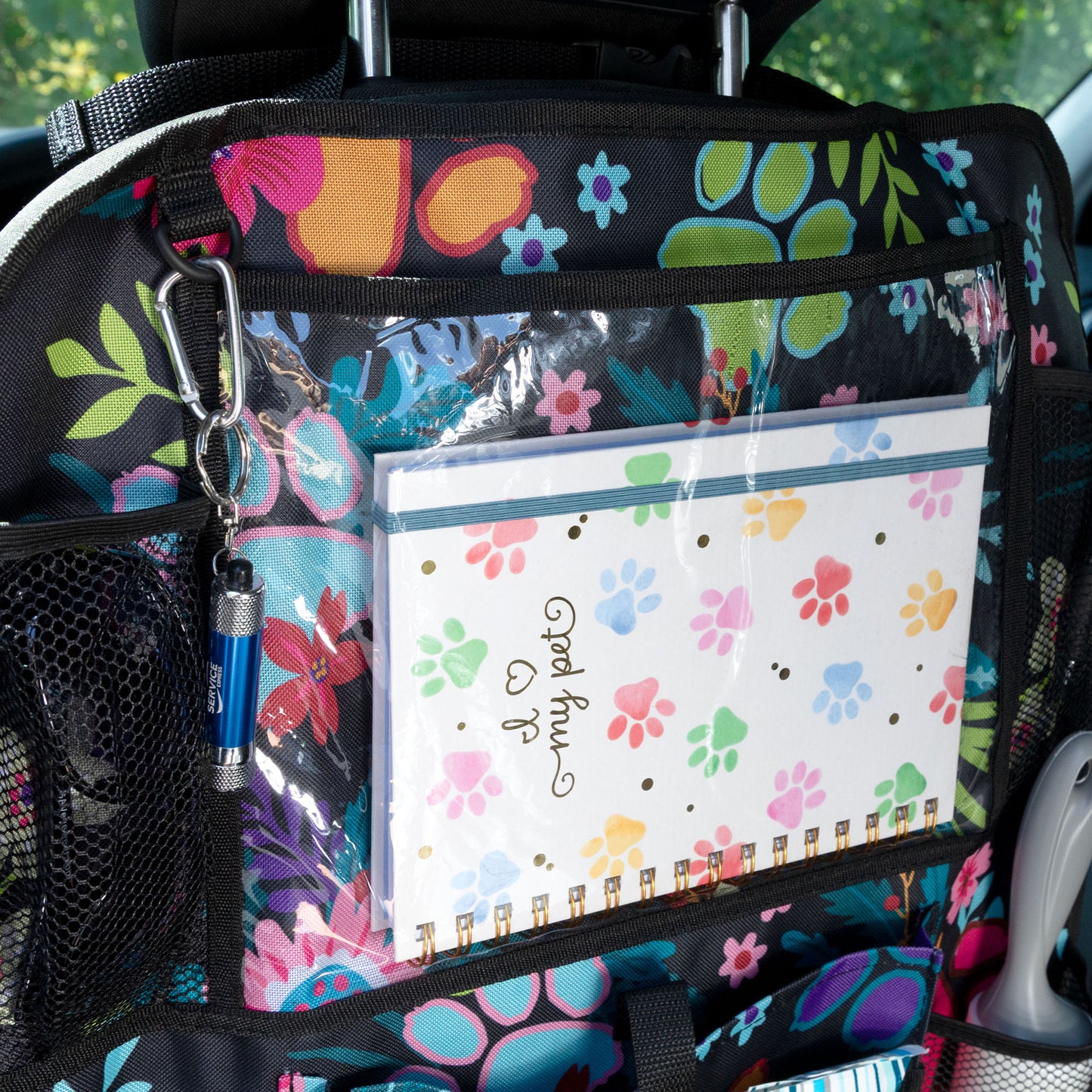 Car organizer with colorful paw print design and a clear pouch containing stationery items.
