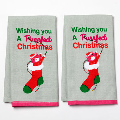Two Christmas-themed kitchen towels with a artistic drawn cat in a stocking and text saying Wishing You a Purrfect Christmas.