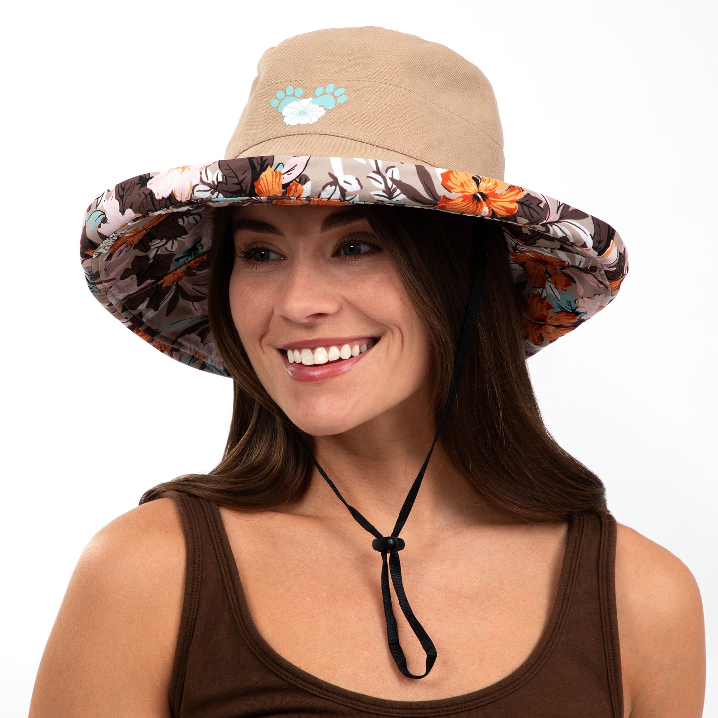 Woman wearing a reversible sun hat with a floral front and beige back on a white background