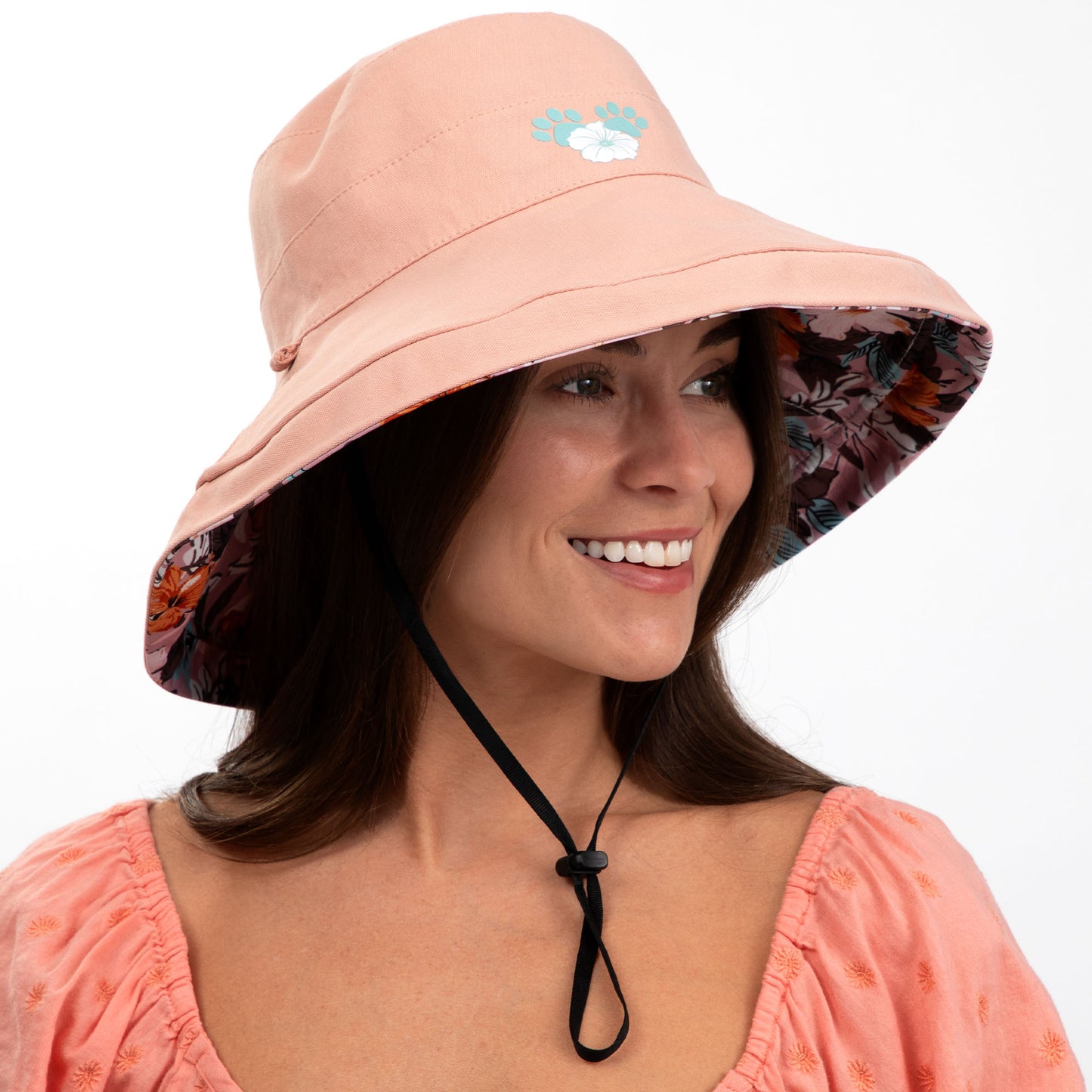 Woman wearing a peach bucket hat with floral interior on a white background