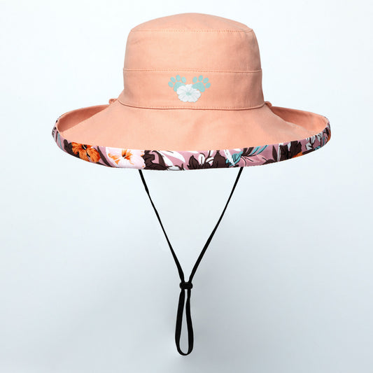 Pink wide brim sun hat with floral band and paw print logo on a light gray background