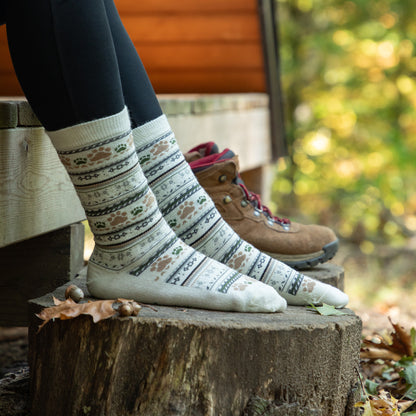 Person wearing patterned socks on a wooden stump with a blurred natural background