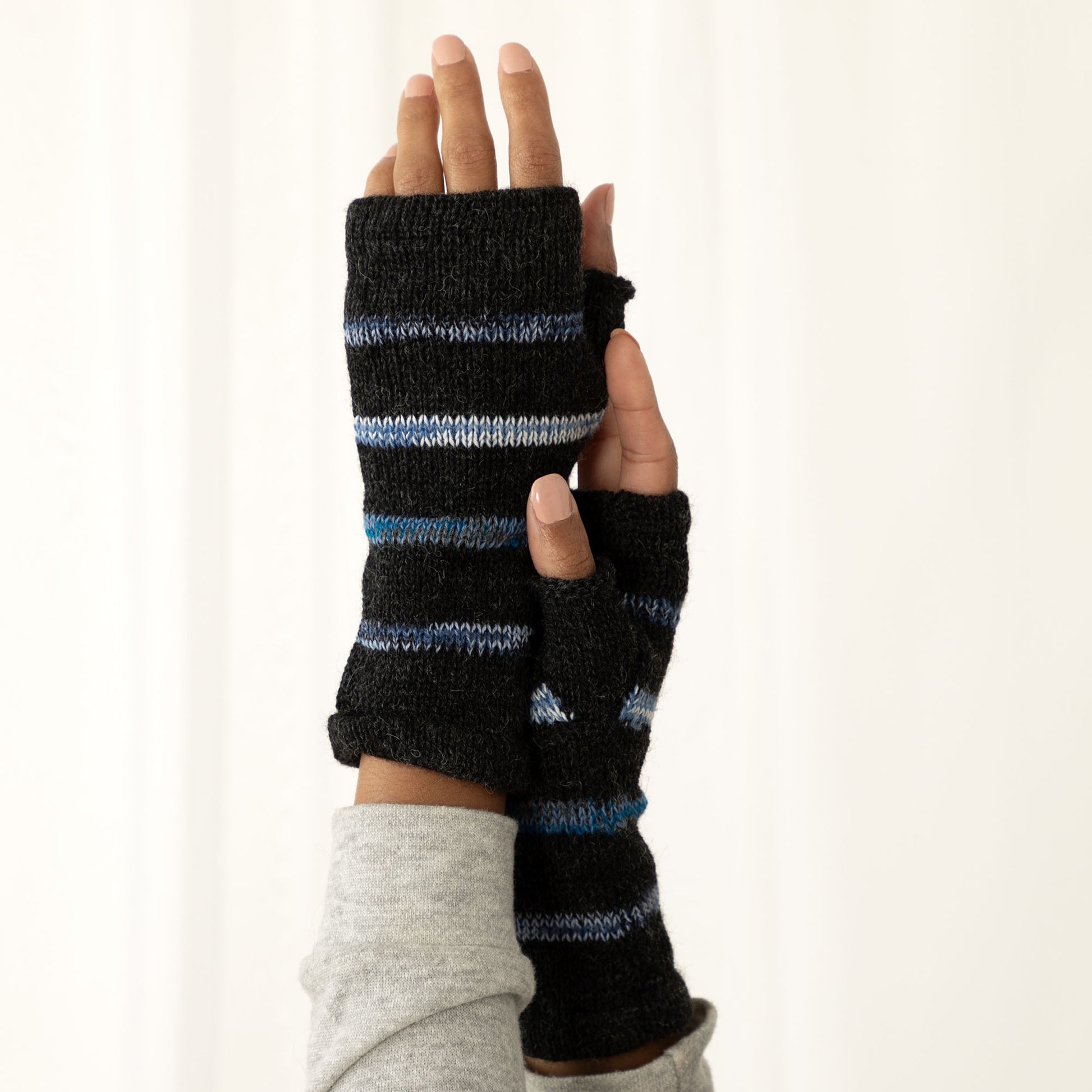 Black and blue striped fingerless gloves worn on a white background
