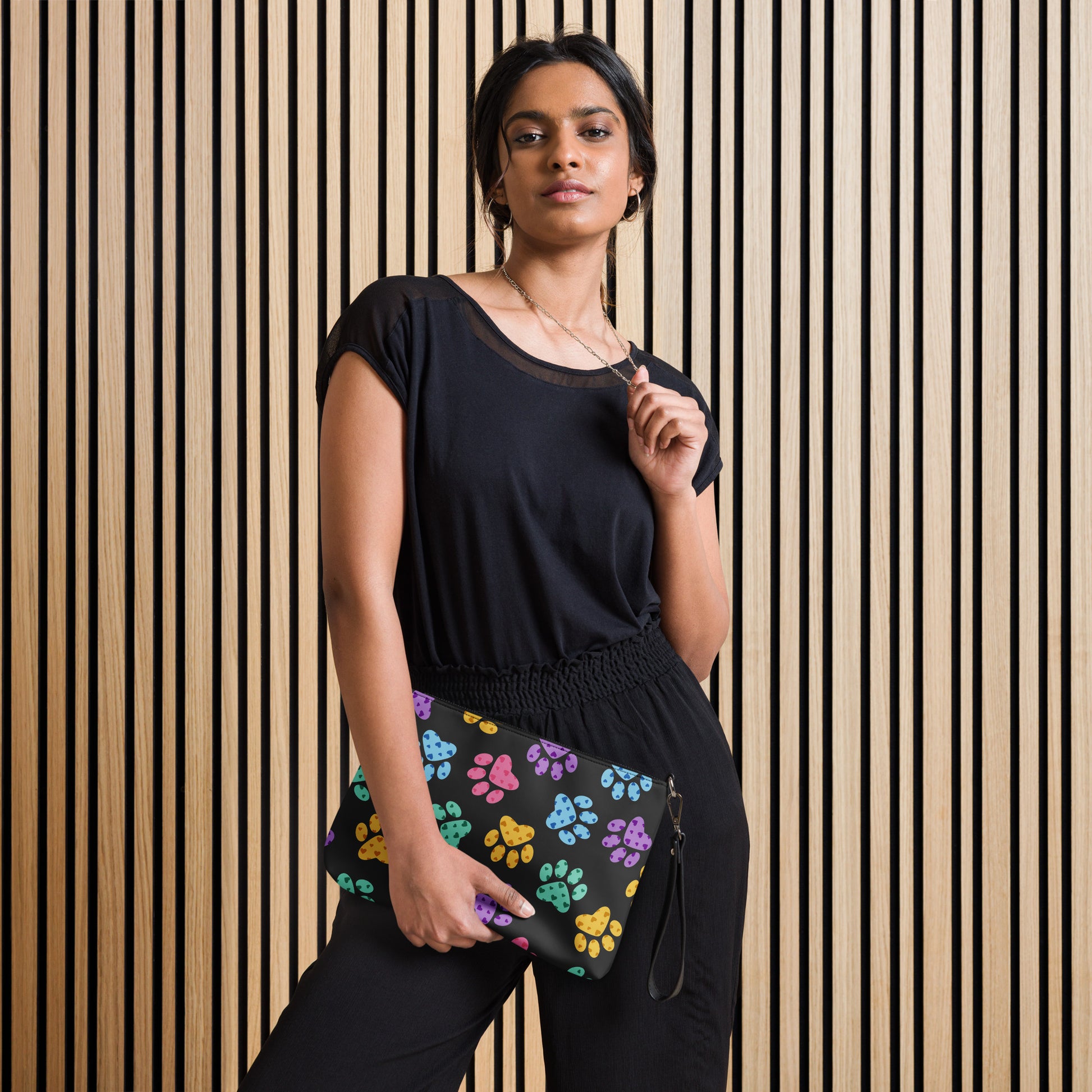Woman holding a colorful paw print bag against a striped wall.