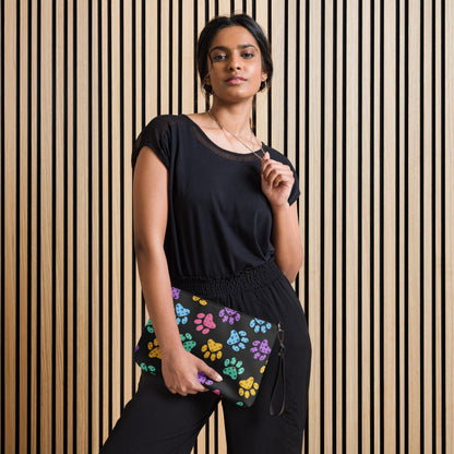 Woman holding a colorful paw print bag against a striped wall.