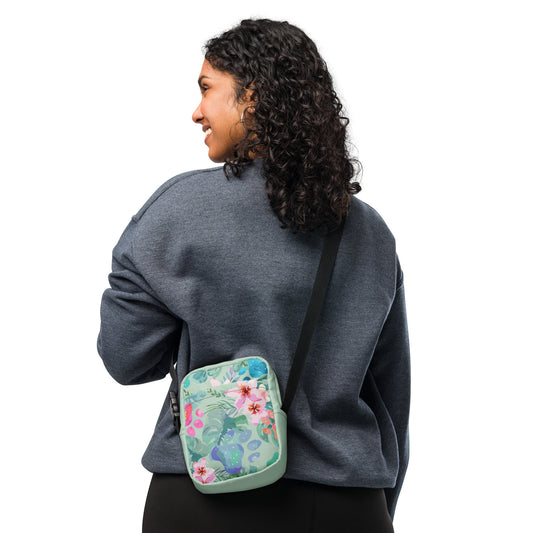 Person wearing a gray sweatshirt with a floral crossbody bag on a white background