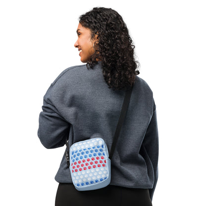 Person wearing a gray sweatshirt with a small blue and red patterned bag on their back against a white background