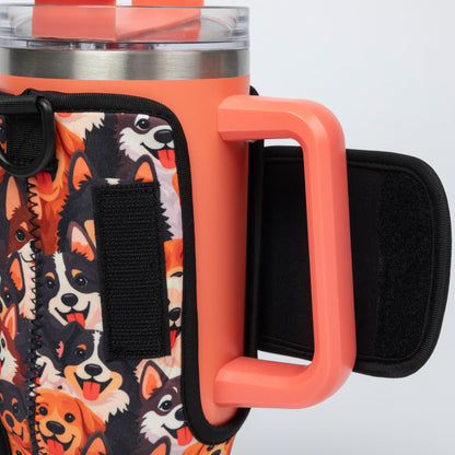 Close-up of a handled insulated tumbler with a coral-orange handle and rim, a stainless steel top, and a dog-print fabric sleeve featuring black velcro straps.