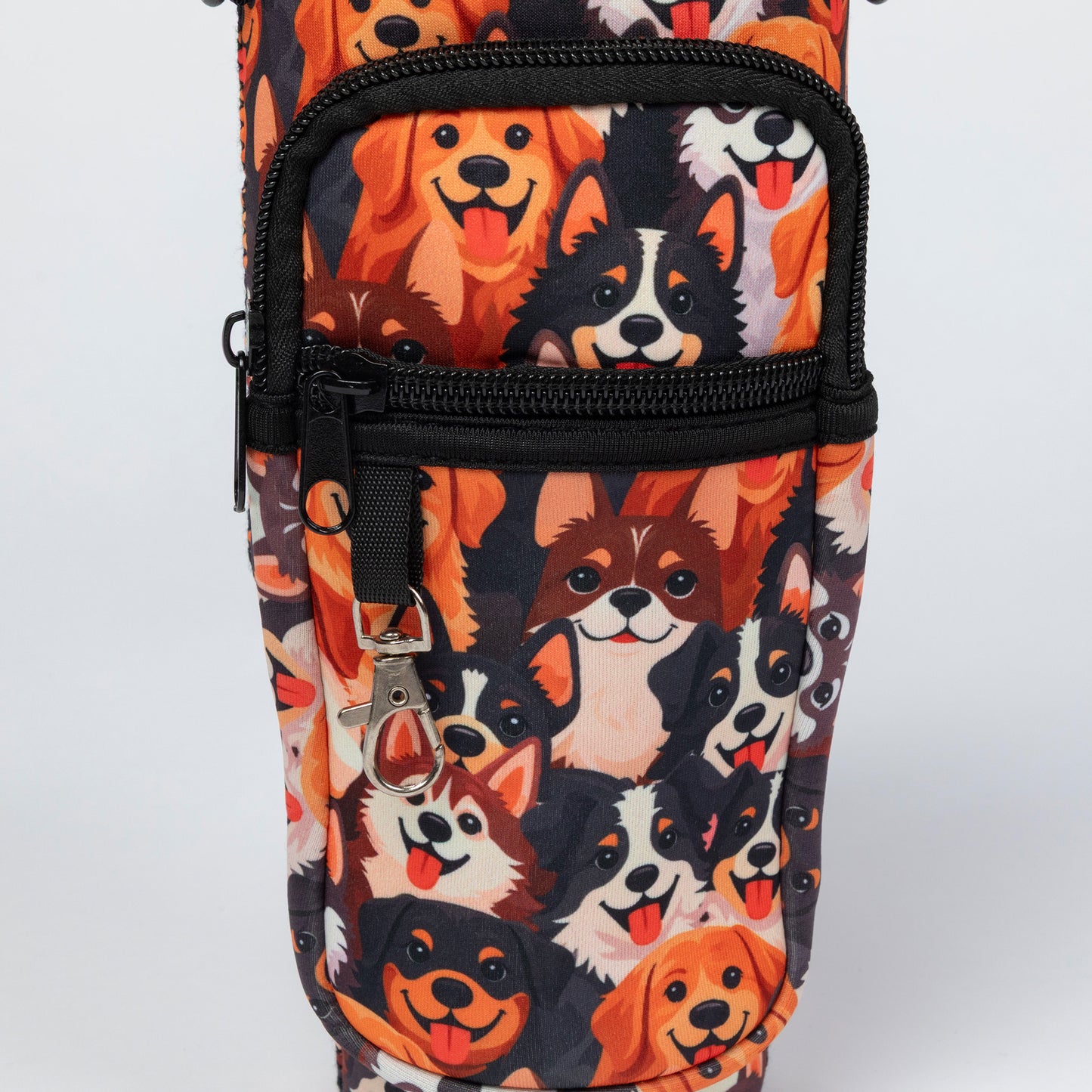 A close-up of a fabric bag or pouch featuring a repeating print of various dog faces in orange, black, white, and brown, with black zippers and a silver keychain clip.