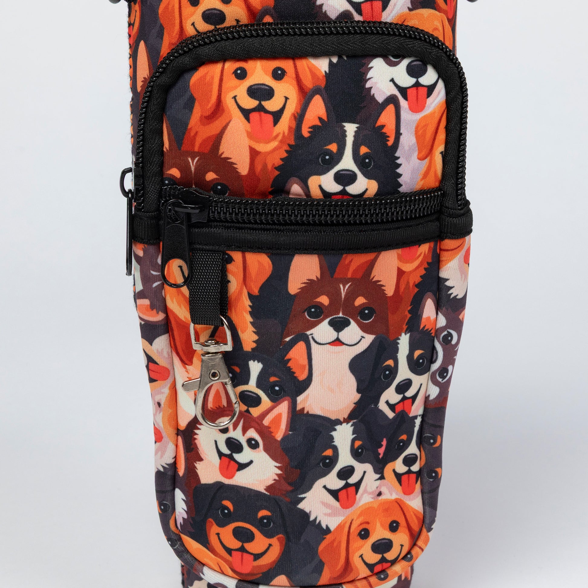A close-up of a fabric bag or pouch featuring a repeating print of various dog faces in orange, black, white, and brown, with black zippers and a silver keychain clip.