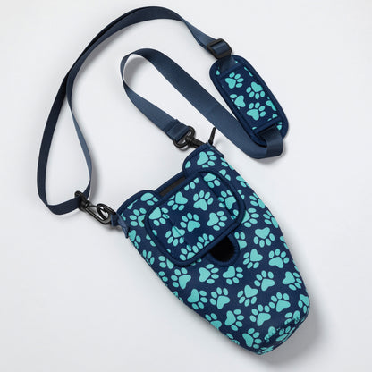 A navy blue pet carrier bag with a repeating mint green paw print pattern, featuring a matching adjustable shoulder strap and padded hip pad, shown on a clean white background.