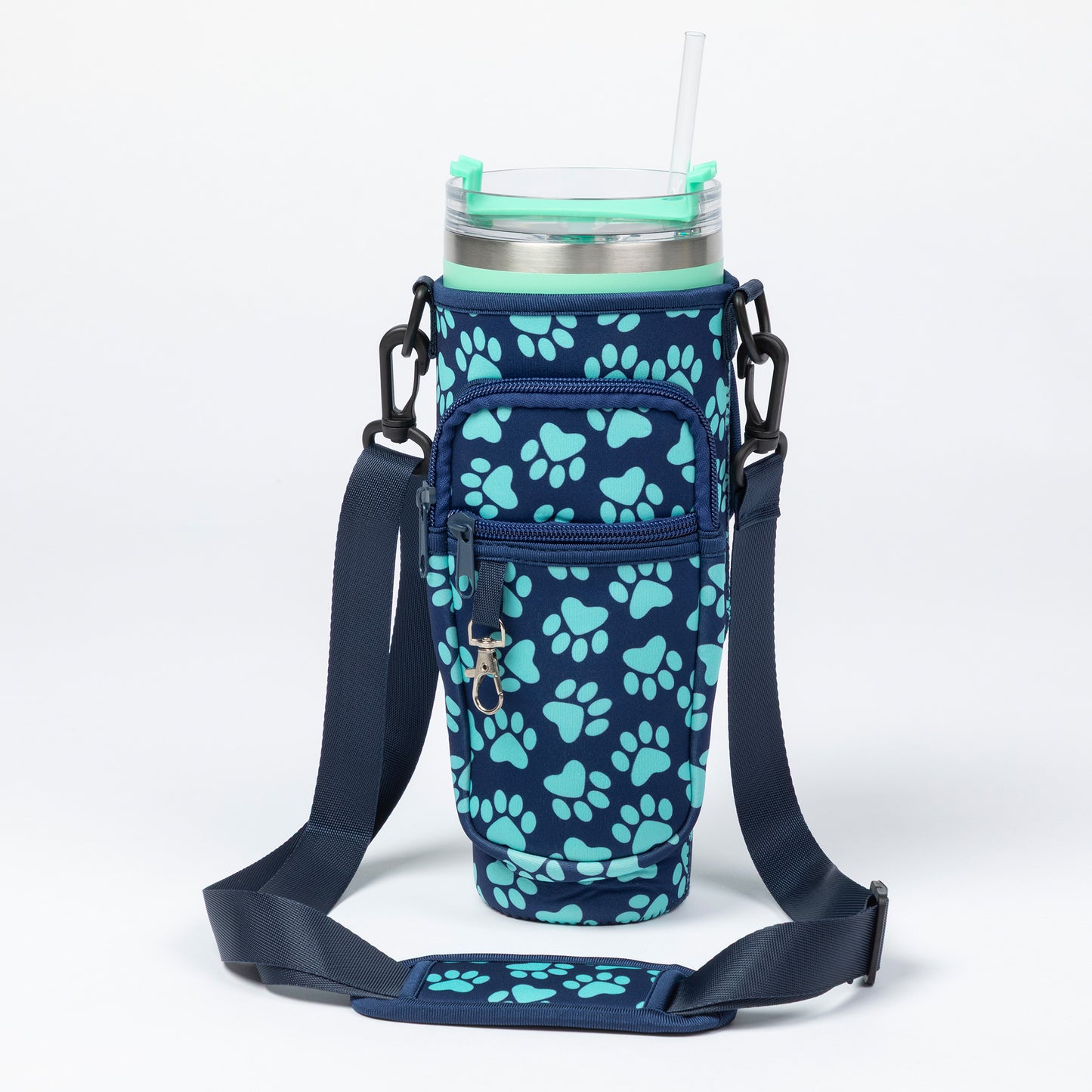 A navy blue insulated tumbler sleeve with a light blue paw print pattern, featuring an adjustable shoulder strap and a clear straw on a white background.