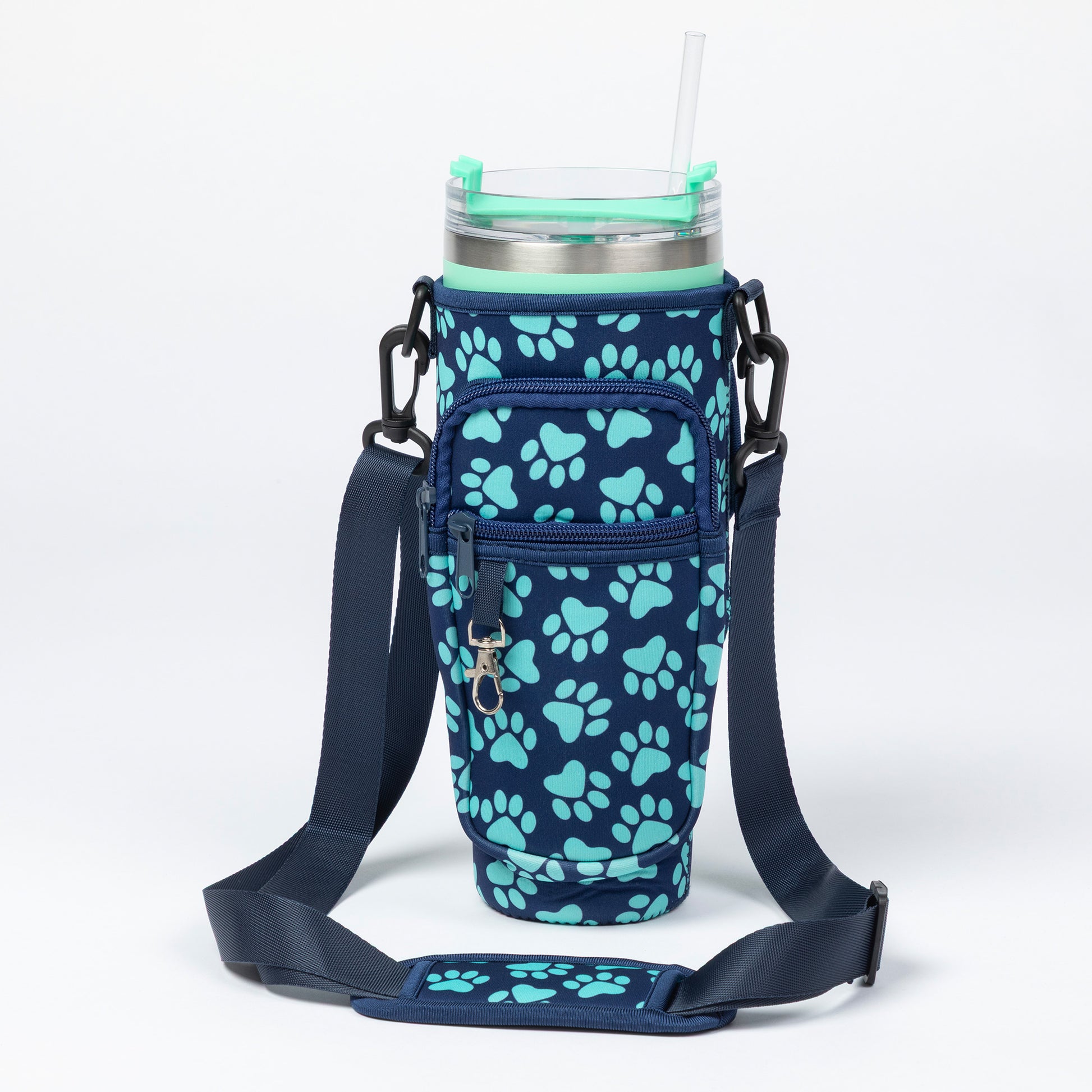 A navy blue insulated tumbler sleeve with a light blue paw print pattern, featuring an adjustable shoulder strap and a clear straw on a white background.
